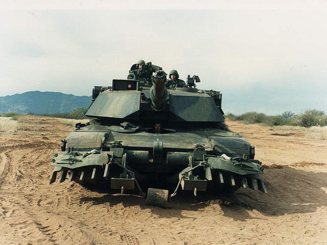 M1 Abrams tank with mine plow, in forest camo (front)